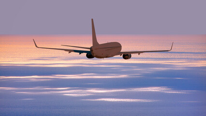 Airplane flying over tropical sea at sunset
