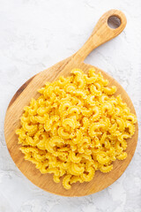 Italian pasta Creste Di Gallo on a wooden board. Rooster scallop. Vertical orientation, top view.