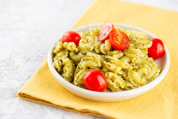 Pasta Creste Di Gallo with cherry tomatoes and pesto sauce in a plate.