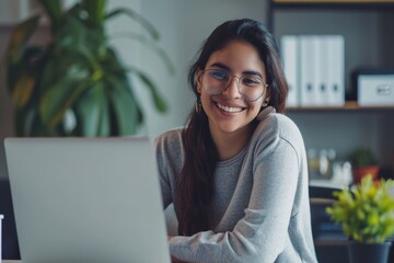A smiling woman working on her laptop in an office setting