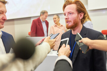 Male speaker talking to journalists with phones at conference