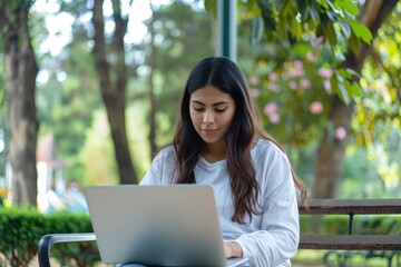 A beautiful woman working on her laptop in a park