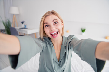 Selfie photographing blonde lady wearing gray pajama making own blog in social medias her morning...
