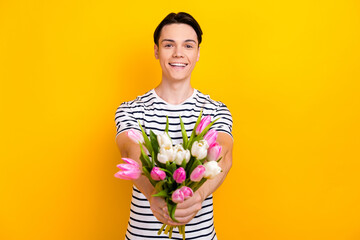 Photo of positive student dressed striped t-shirt presenting you bouquet of flowers on valentine...