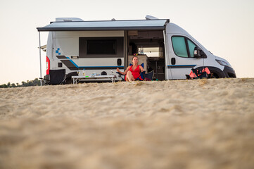 Campervan or motorhome parked on the beach in Greece. Touristwoman enjoying and relaxing on the...