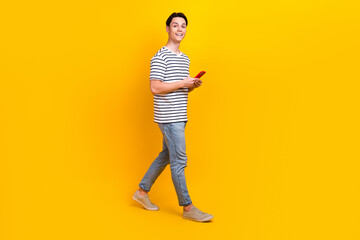 Full size photo of optimistic student dressed striped t-shirt hold smartphone go to empty space...