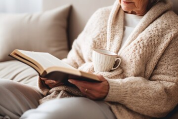 An old woman sits on a bed surrounded by pillows and reads a funny book. - Powered by Adobe