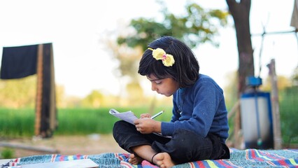 Back to school concept. Poor Children Lifestyle. Education concept. School boy doing homework, writing on copy book in green grass of park.