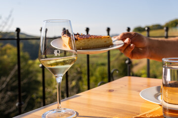 A golden hour setting with a glass of white wine and a slice of pie on a round wooden table,...