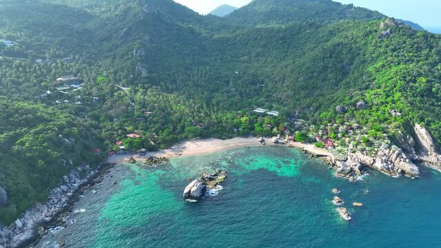 Sandy coastline dotted with verdant trees, a picturesque resort enclave framed by transparent azure waters. Pure tranquility beckons. Drone aerial view. Koh Tao, Southern Thailand. Sea background.
