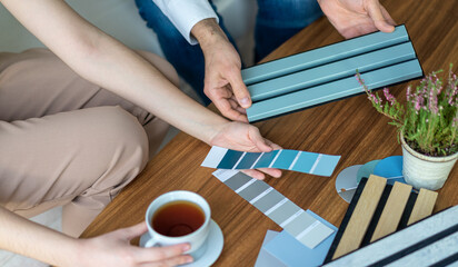 Interior designer and customer choosing home design materials from acoustic panel samples in the...