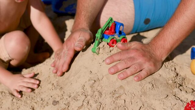 Father and 3 years son on beach building sand castle with plastic toys hands closeup . single father solo parent. Involved parenting. Relaxing and playing outdoors with family