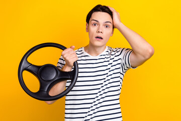Photo of confused astonished student dressed striped t-shirt holding steering wheel arm on head...