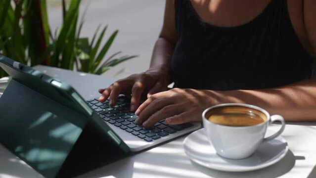 Woman typing at tab computer in coffee shop. Concept designer and IT. A freelancer is working on a project.