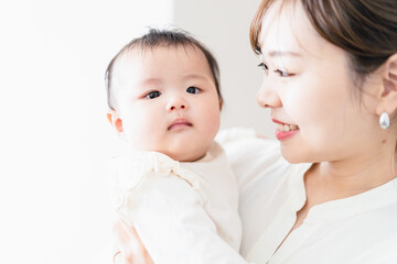 赤ちゃんを抱っこしながら家事をする若い女性