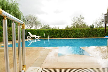 Blue pool in green garden cloudy day