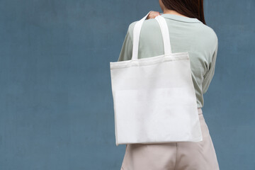 Blank white tote bag canvas fabric with handle mock up design. Back view of woman holding eco or...