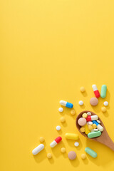 A large amount of medication and a wooden spoon filled with medication on a yellow background. Medical Health Concept