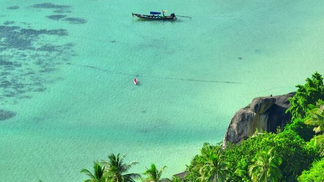 Lush coastal forests blend with distinctive rocky outcrops, harmonizing with the mesmerizing hues of the pristine turquoise sea along the shore. Flight over the ocean. Koh Tao, Southern Thailand. 4K. 