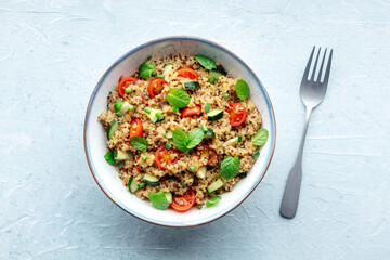 Quinoa tabbouleh salad in a bowl, a healthy dinner with tomatoes and mint, overhead flat lay shot with a fork - 746526554
