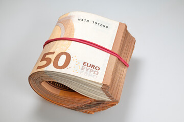 Fifty euro bills banknotes on a grey table rolled and tied with red rubber band