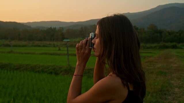 Young woman takes photos 0f the rice fields at sunset