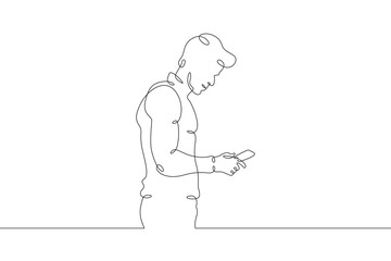 Fototapeta na wymiar A man stands with a phone in his hand. A man is talking on a smartphone. One continuous line . Line art. Minimal single line.White background. One line drawing.