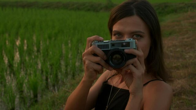 Portrait of a young woman with a retro camera in nature