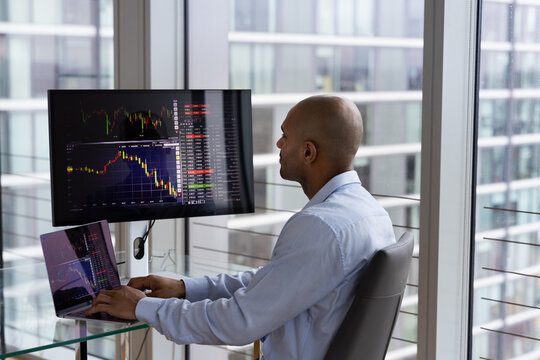 Stock trader looking at stocks and shares on computer in a high rise office
