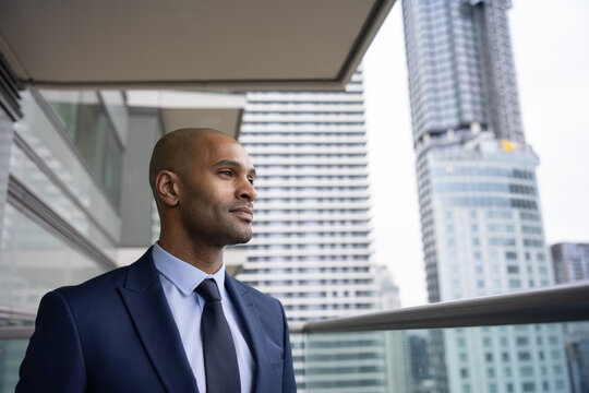 African American businessman on office balcony looking confidently at city skyline