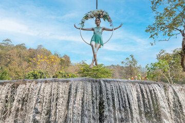 Beautiful Asian woman playing Rig and Hang Aerial Hook for Yoga in Nature scenery.