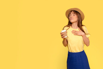 Happy young redhead woman in Happy young redhead woman holding and drink craft cup of coffee or tea  on  yellow background  holding and drink craft cup of coffee or tea  on  yellow background