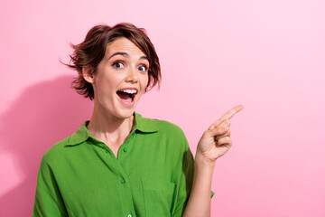 Photo portrait of attractive young woman excited finger point empty space dressed stylish green clothes isolated on pink color background