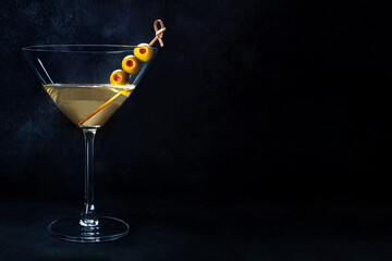 Martini. A glass of dirty martini cocktail with vermouth and olives, aperitif, on a black background, with copy space