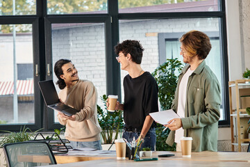 Three young men engaged in a lively discussion over a laptop at a coworking space, startup ideas