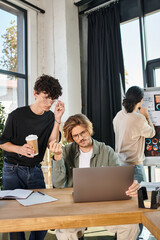 young businessmen evaluating data on laptop with coworker looking at charts on background, startup