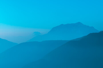 Spectacular mountain ranges silhouettes in shades of light blue.