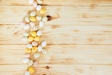 Multi-colored chocolate decorative eggs on a wooden background. Happy Easter background. Top view