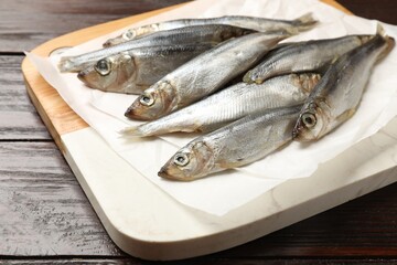Fresh raw sprats on wooden table, closeup