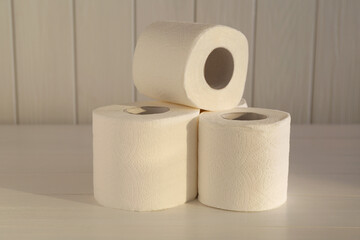 Many soft toilet paper rolls on white wooden table