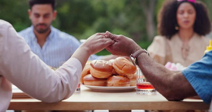 Holding hands, prayer and food with thanks, religion and backyard with family and lunch. Faith, worship and praying at a table for blessing together on a patio outdoor from a home at a gathering