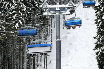 Skiers on blue modern ski lift in winter resort.