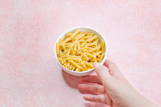 Mano recogiendo un plato de pasta cruda