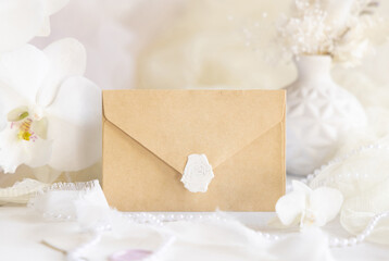 Sealed envelope near white orchid flowers and decor close up, pastel romantic wedding mockup