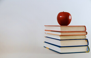 The apple– a symbol of knowledge that gives a taste of a transparent mind, lies on a stack of books, like a path to wisdom that opens page by page.