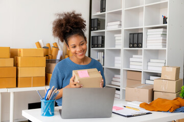 Startup, small business, African woman business owner using a smartphone or laptop to receive and verify online orders in order to prepare boxes of packed products for delivery. SME business concept