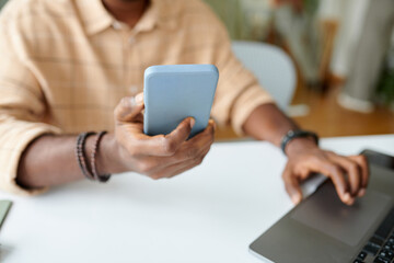 Entrepreneur checking notifications on smartphone when working in office