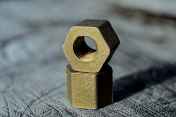 Brass hex nuts layed out on a wood