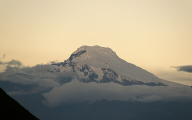 Volcán nevado en el atardecer rodeado por nubes