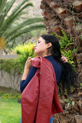 Retrato de una mujer blanca, latina, hermosa de cabello negro con chaqueta roja y una blusa azul,...